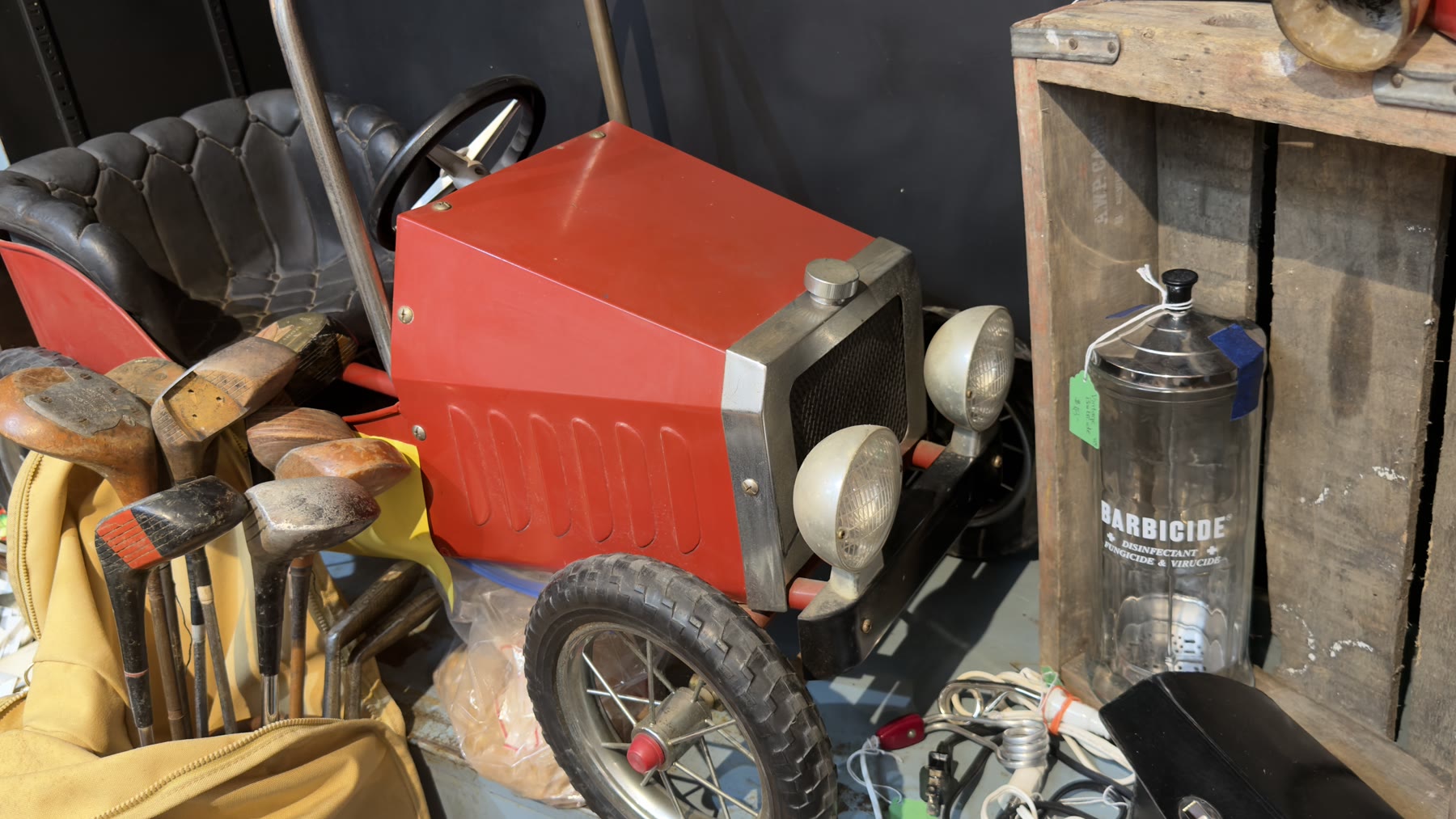 Vintage red pedal car with vintage golf clubs and a Barbicide jar