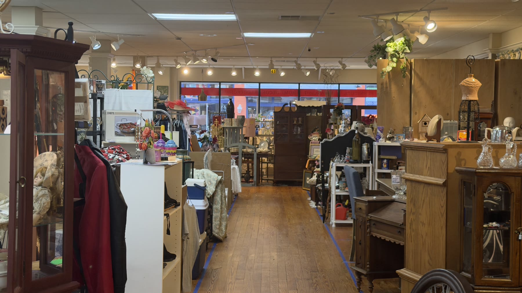 Wide interior view across a wood-floor aisle toward the storefront windows
