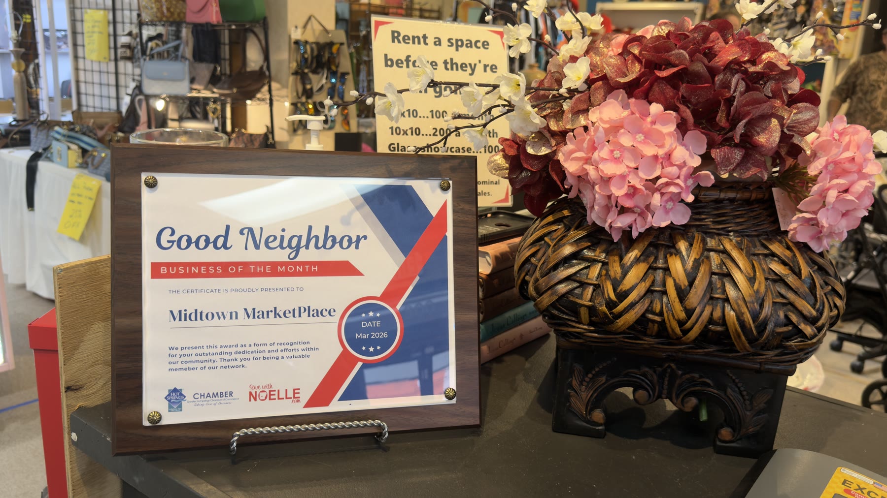 Good Neighbor Business of the Month certificate awarded to Midtown Marketplace, March 2026, displayed beside a basket of pink hydrangeas